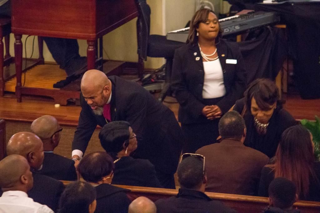 People in a church setting, some seated, some interacting with others, possibly a service or gathering.