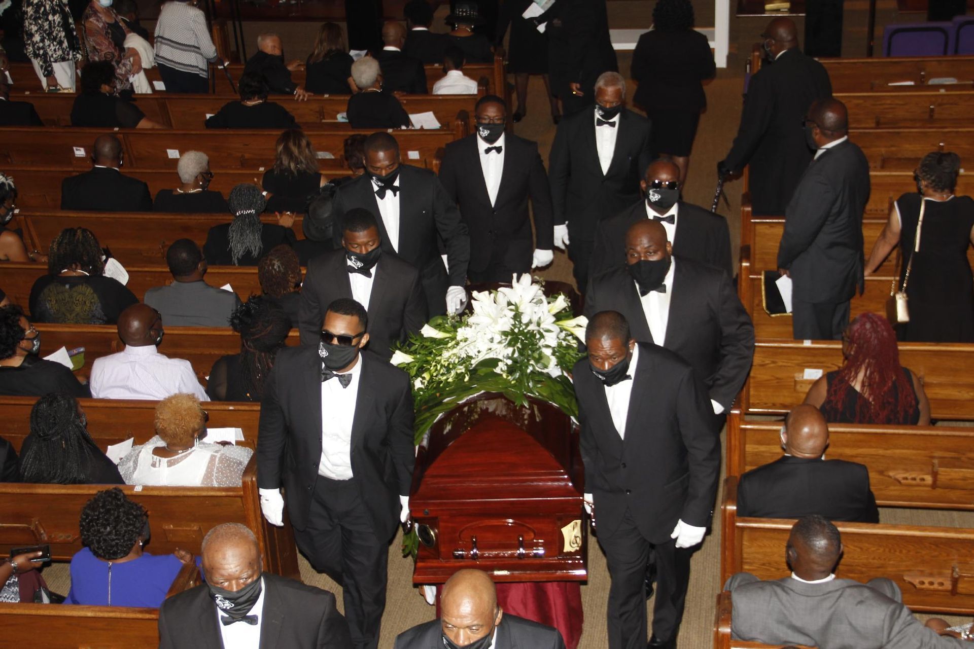 Pallbearers carrying a casket out of a church during a funeral service.