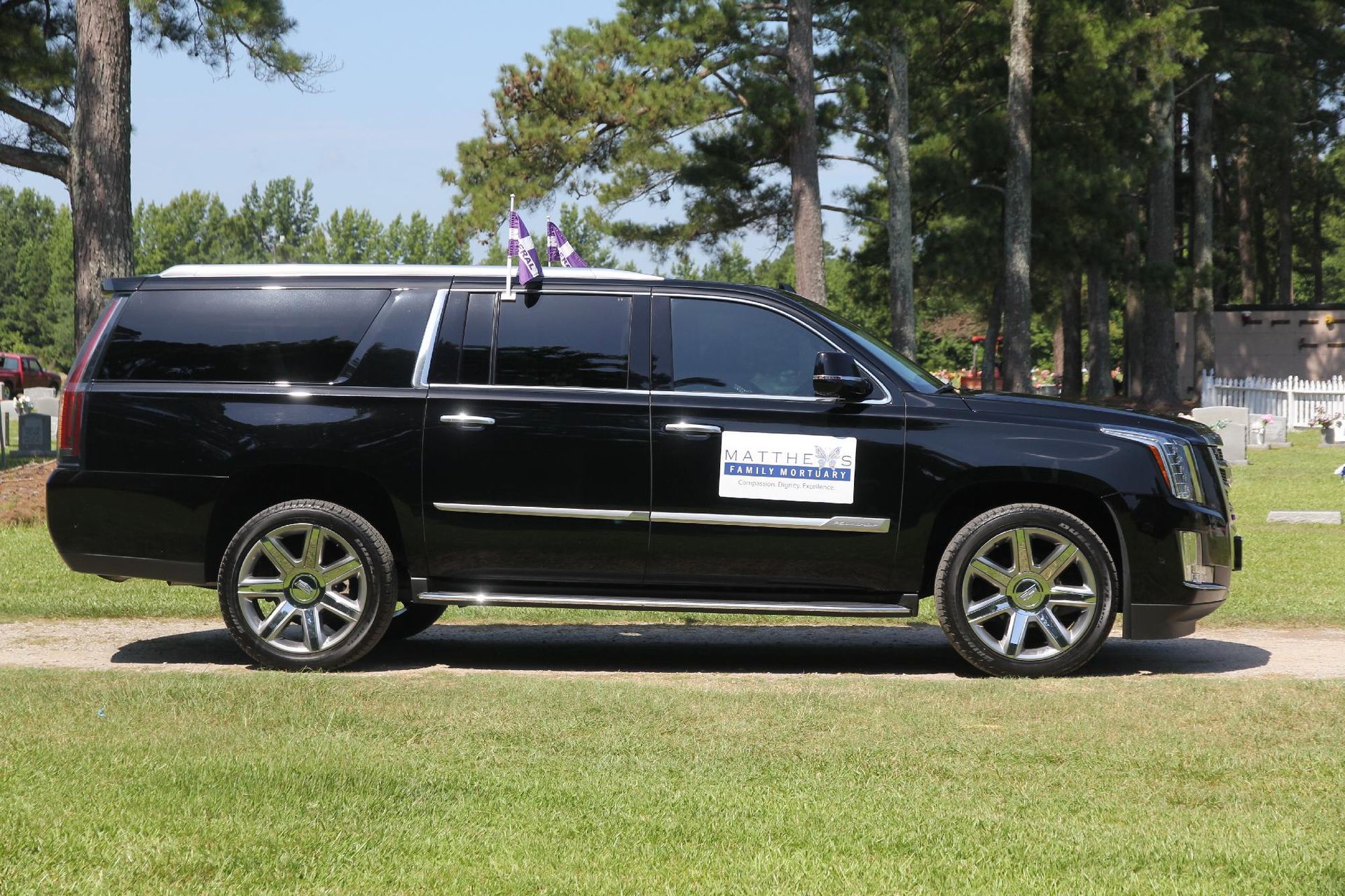Black SUV with tinted windows parked on grass in a cemetery.