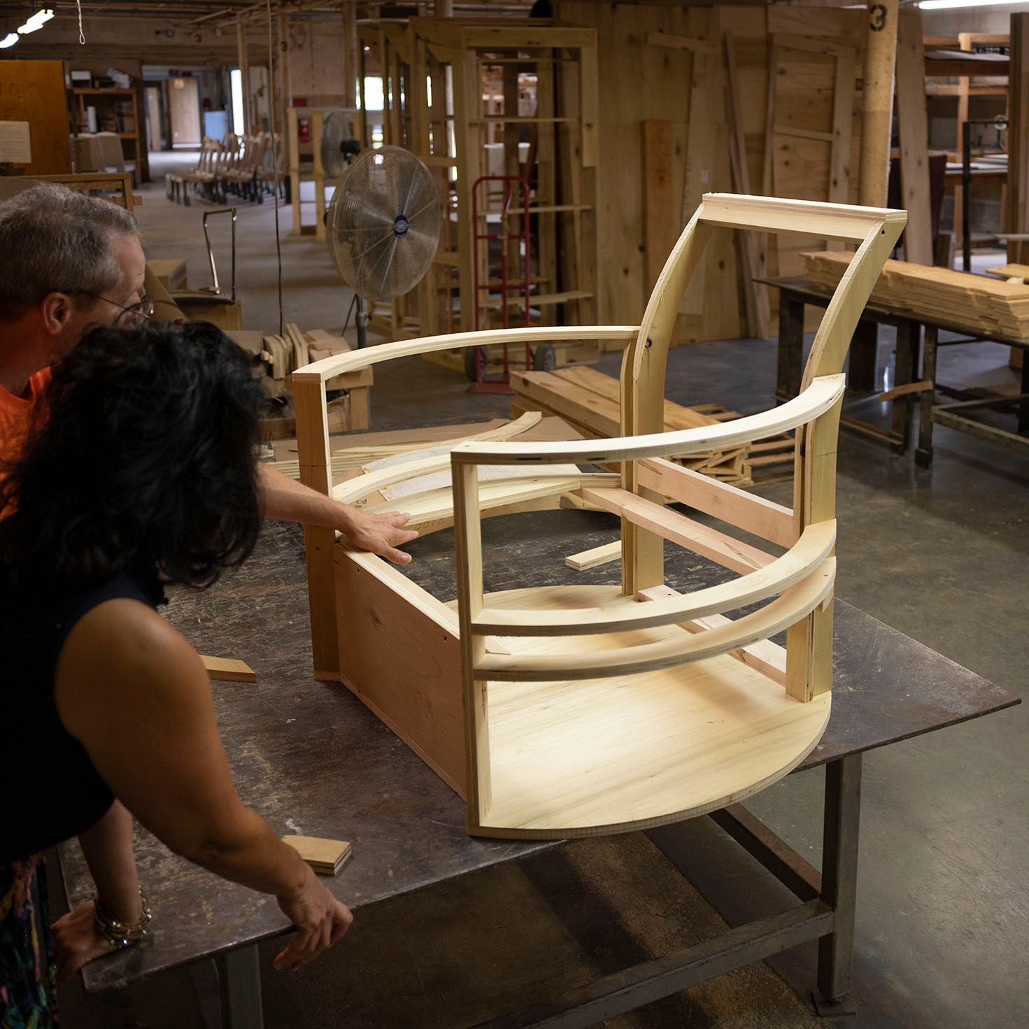 A man and a woman are looking at a wooden chair on a table