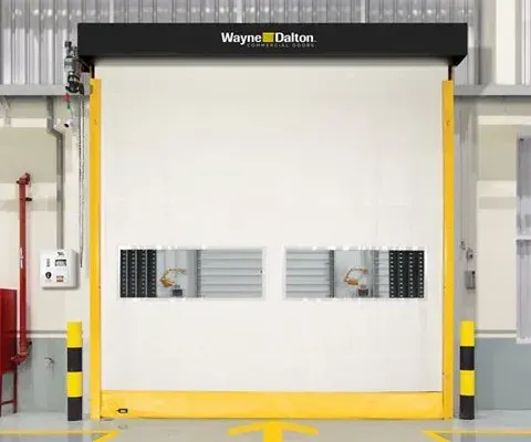 Wayne Dalton industrial high-speed door, cream-colored, with two rectangular windows and black and yellow bumpers.