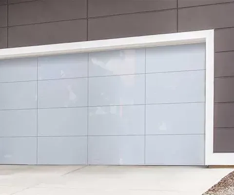 Modern garage door with white panels, framed in white, set against a dark grey wall.