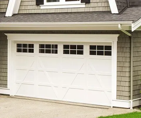 White garage door with four window panes and cross paneling, framed with white trim.