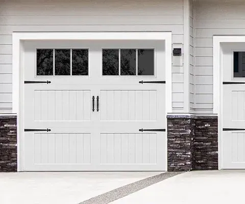 White garage door with windows, black hardware, and stone accents.