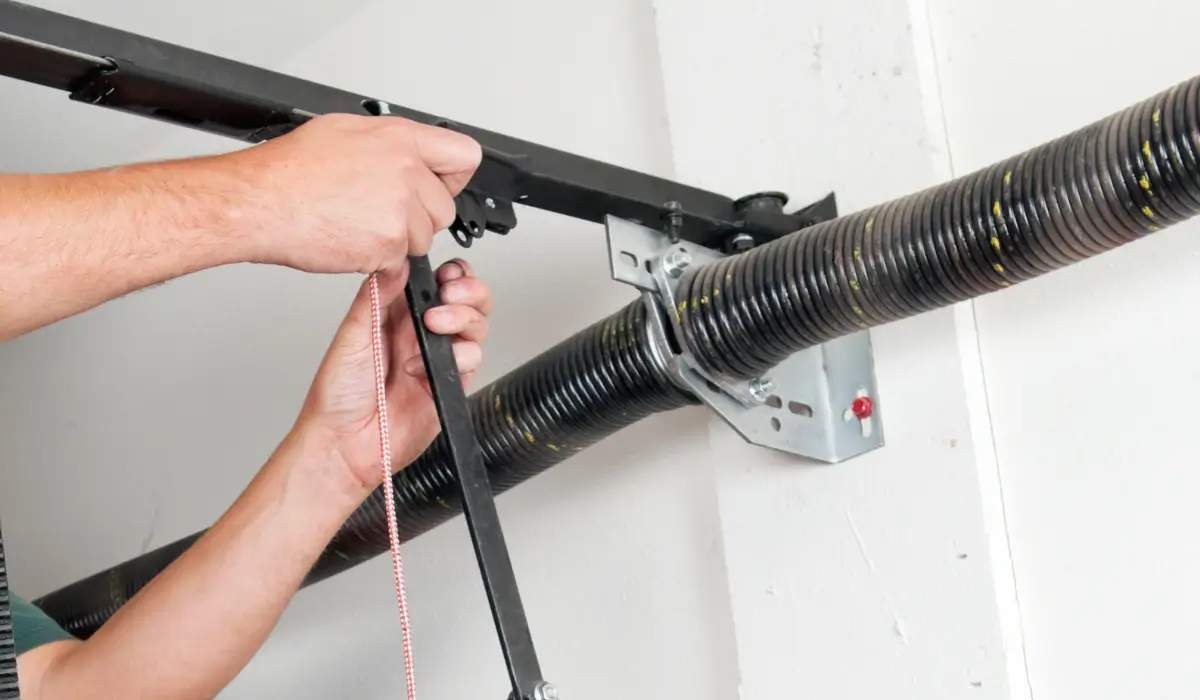 Person adjusting garage door spring, using a winding bar.