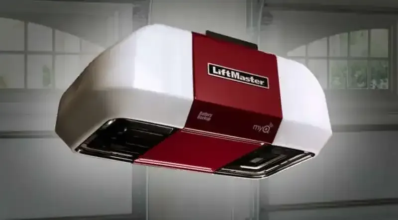 A LiftMaster garage door opener, white and red, hangs in a garage.