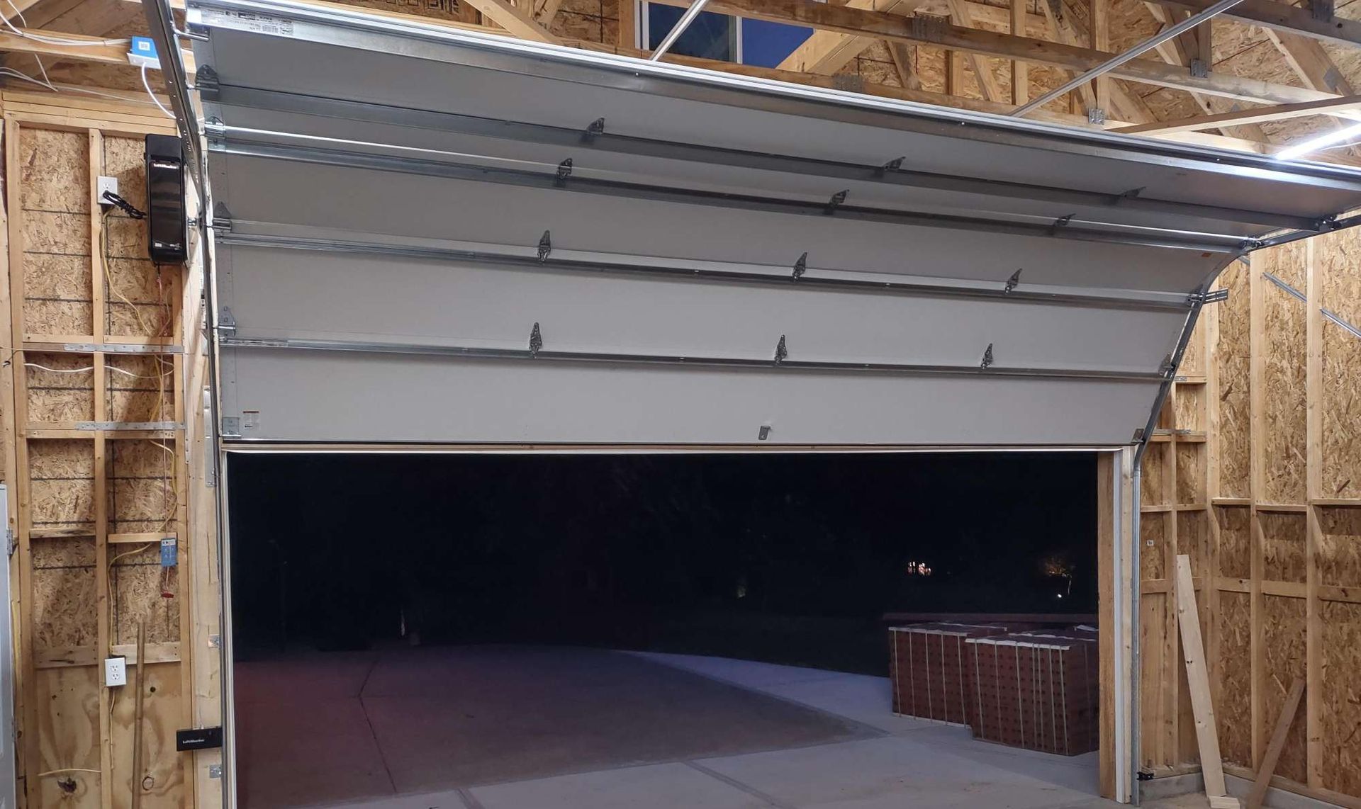Garage door partially open, revealing a dark exterior. The door is white and the framing is wooden.