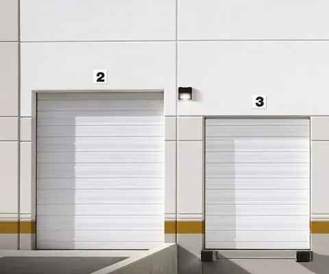 Exterior view of a white industrial building with two closed loading dock doors labeled