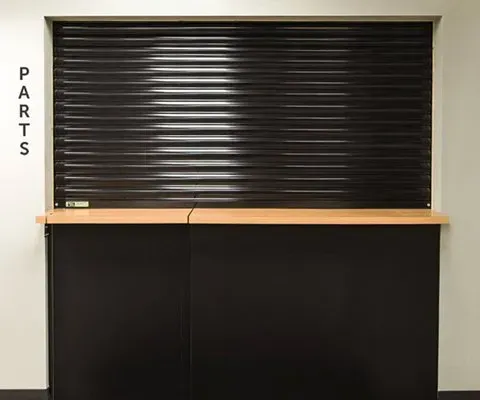 Black parts counter with closed roll-up door, beige countertop,