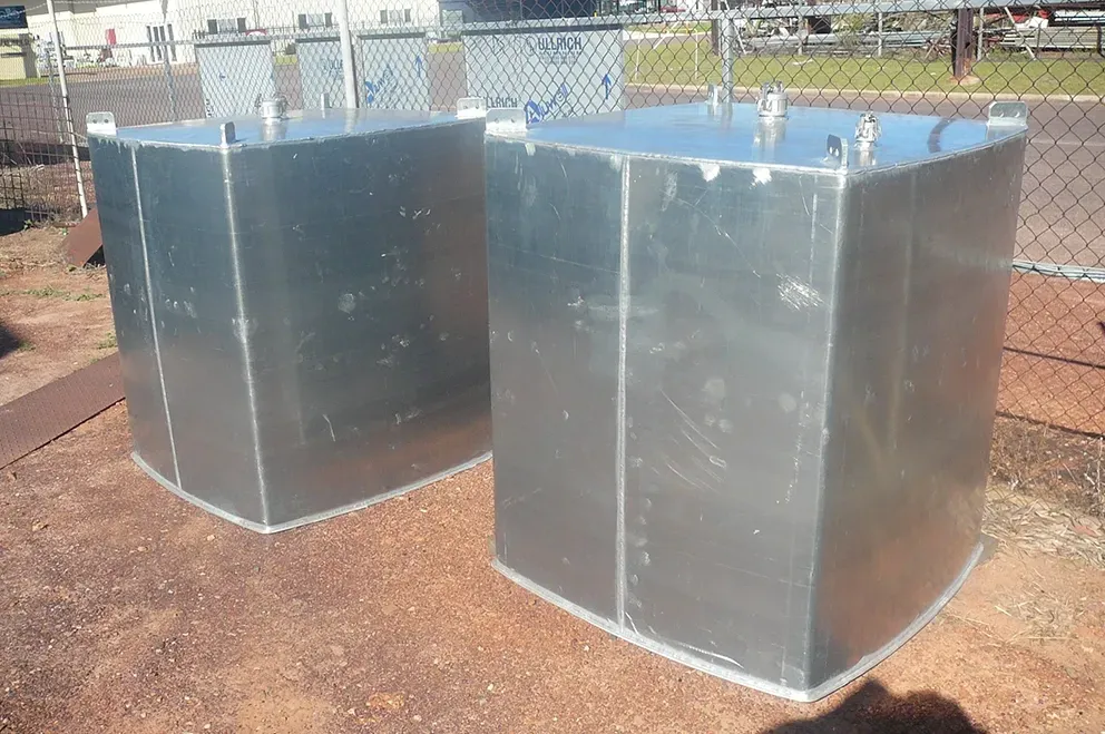 Two Large Silver Metal Storage Tanks Outdoors on Reddish Gravel Near a Fence — Greville Fabrication in Girraween, NSW