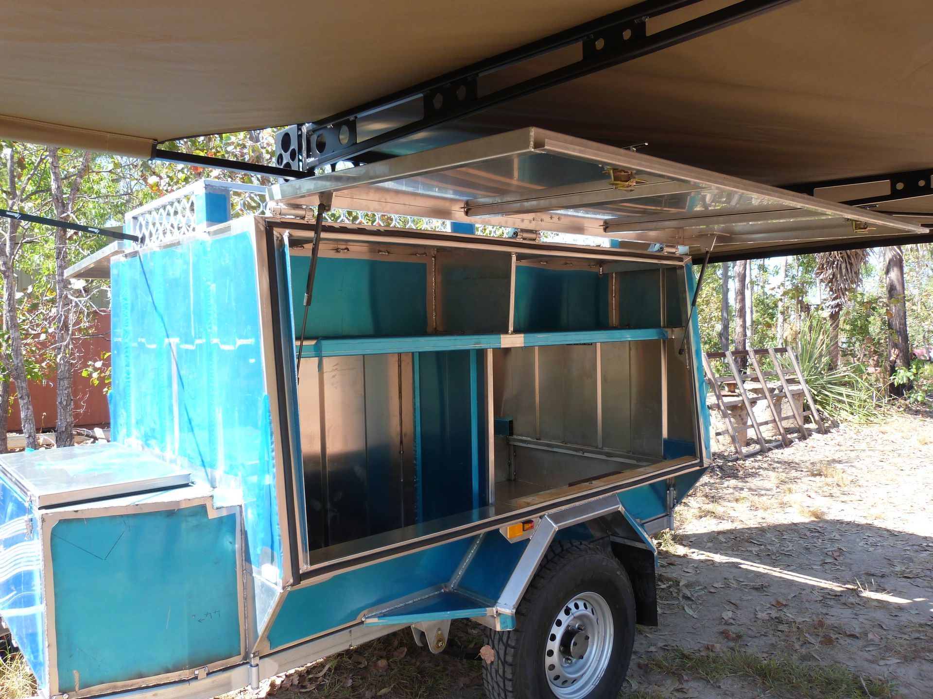 Blue Trailer-mounted Utility Cart With Open Shelves Parked Under a Carport Outdoors — Greville Fabrication in Girraween, NSW
