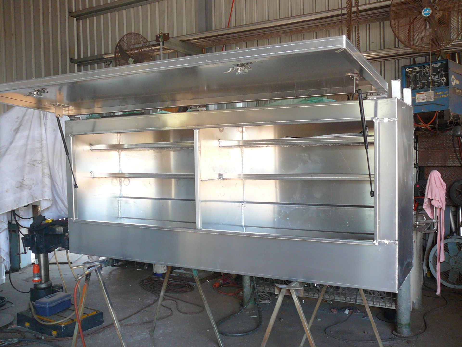 Stainless Steel Display Counter in a Workshop, With Shelves and a Canopy on Top — Greville Fabrication in Girraween, NSW