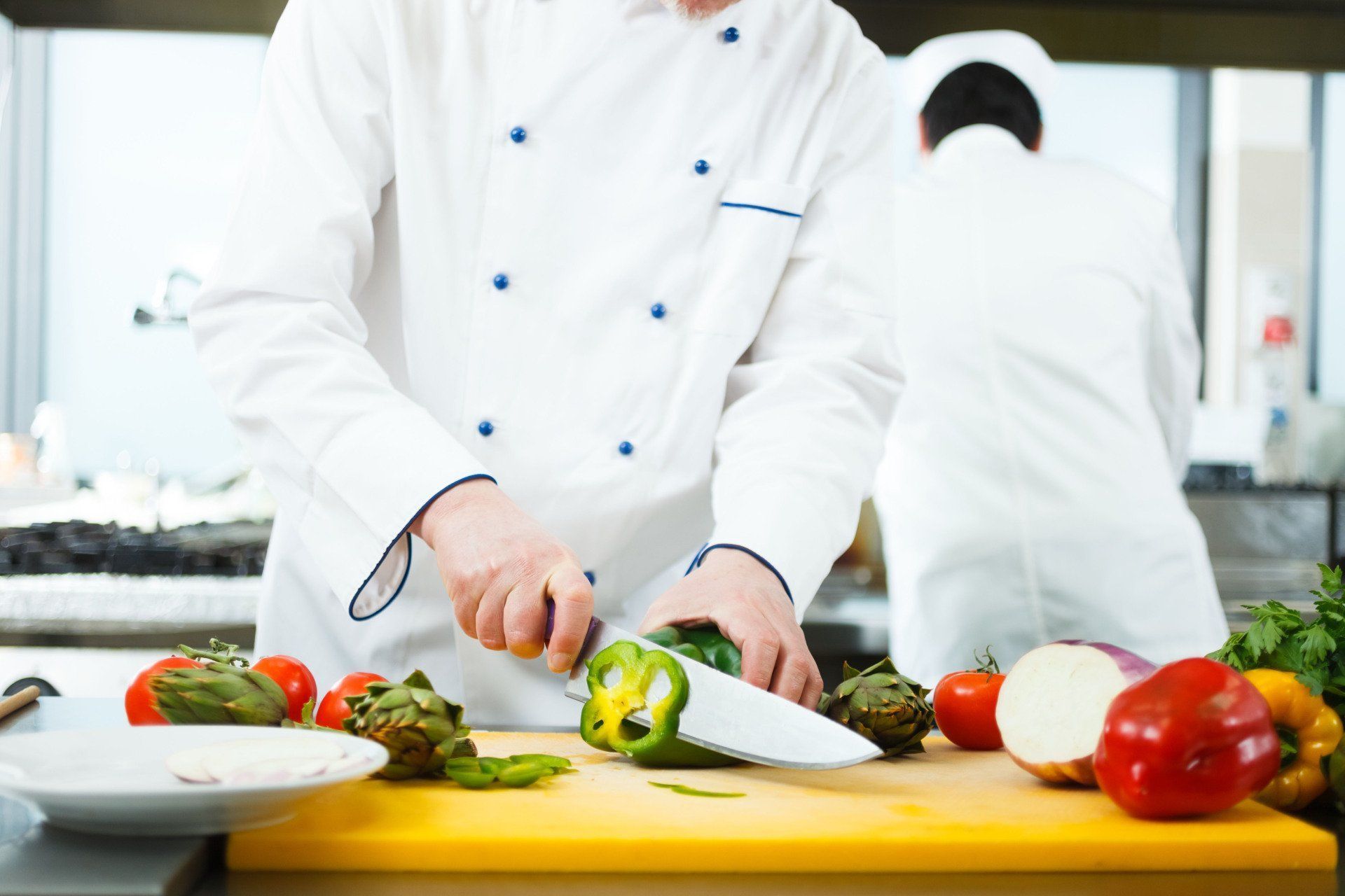 A chef is cutting vegetables on a cutting board in a kitchen.