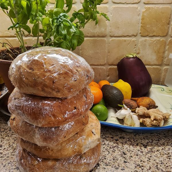 A stack of bread sits on a counter next to a plate of fruit and vegetables