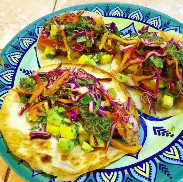 Three tacos on a green plate with a blue border