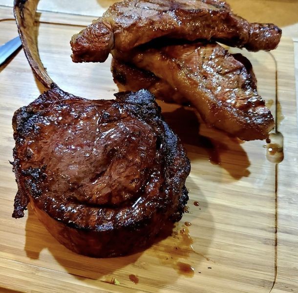Two pieces of meat are on a wooden cutting board