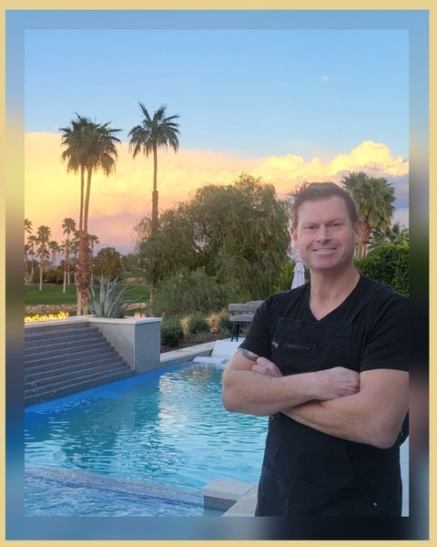 A man is standing in front of a swimming pool with his arms crossed.