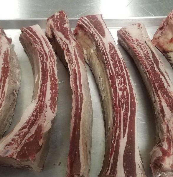 A bunch of meat ribs are lined up on a tray