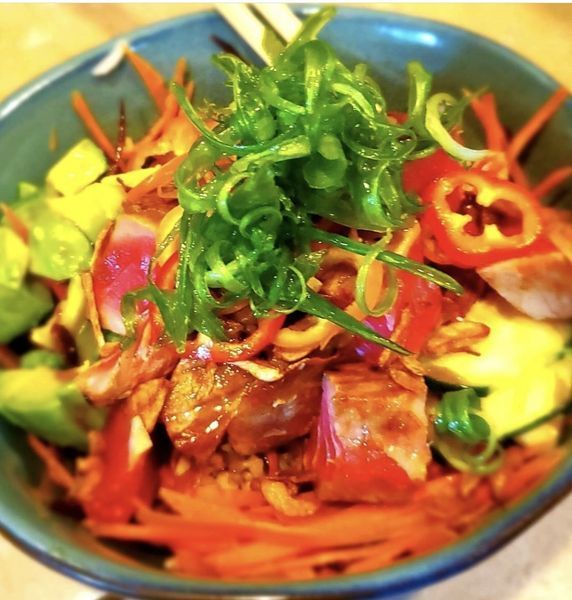 A blue bowl filled with a variety of vegetables and meat