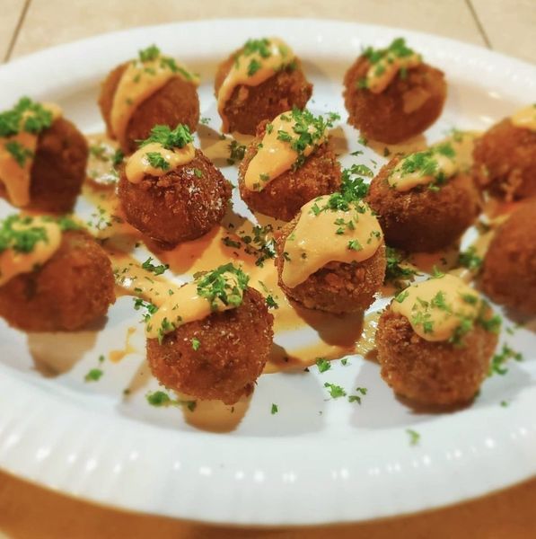 A white plate topped with meatballs and cheese sauce