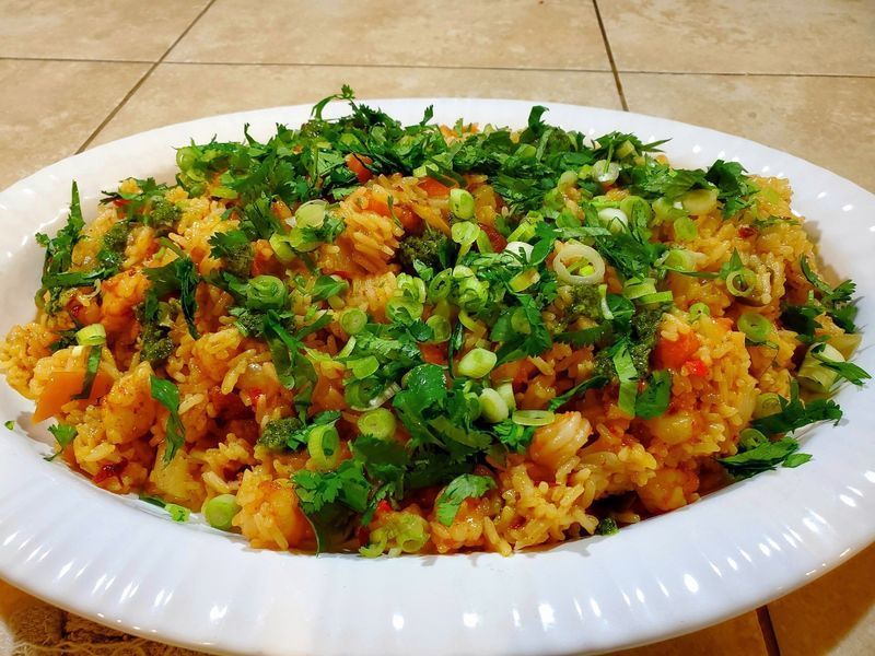 A white plate topped with rice and vegetables on a tiled floor.