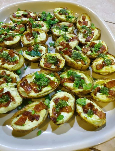 A tray of potato skins with cheese , bacon and green onions