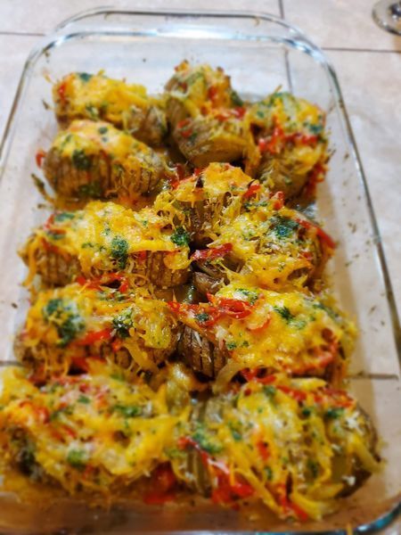 A casserole dish filled with potatoes covered in cheese and vegetables.