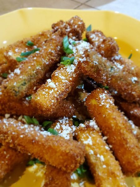 A close up of fried zucchini sticks on a yellow plate