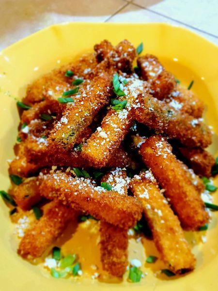 A yellow plate topped with fried zucchini sticks