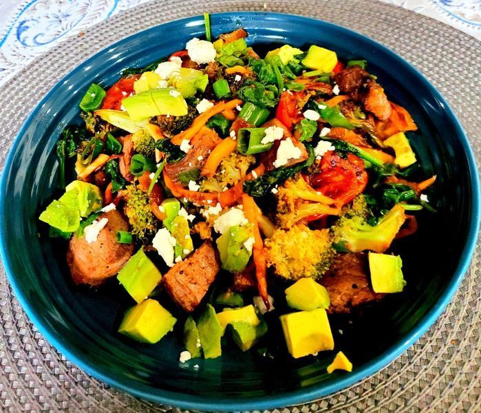 A blue plate topped with vegetables and cheese on a table.
