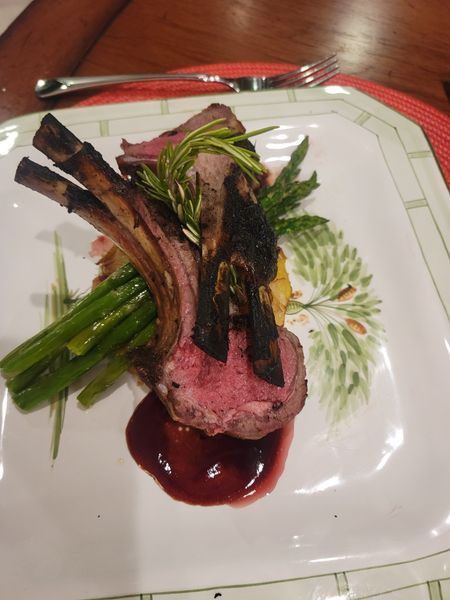 A white plate topped with meat and asparagus on a table