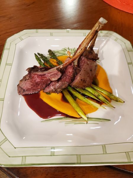 A white plate topped with lamb chops asparagus and mashed potatoes