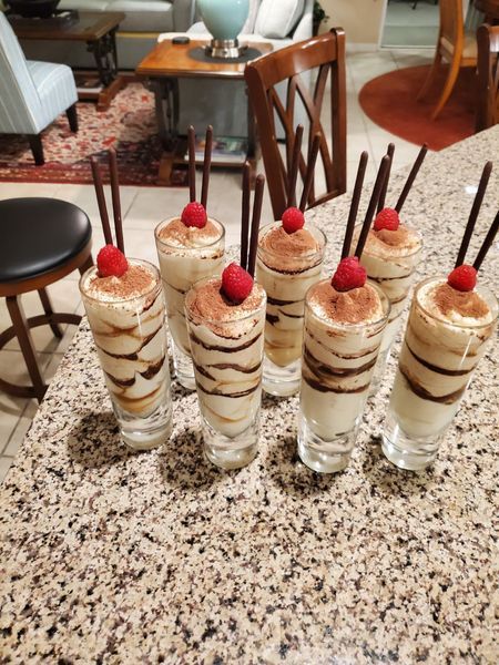 A row of desserts in shot glasses with strawberries on top