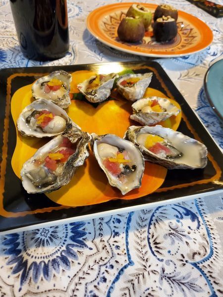 A plate of oysters on a table next to a bottle of wine
