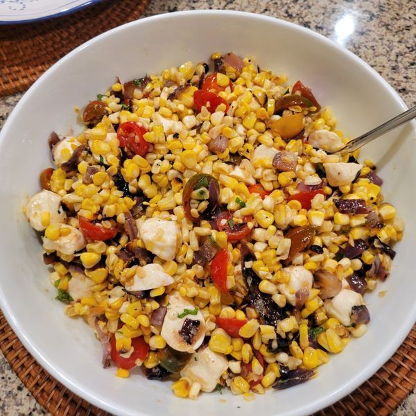 A bowl of corn salad with a spoon in it
