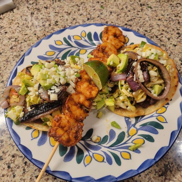 A blue and white plate with a skewer of food on it