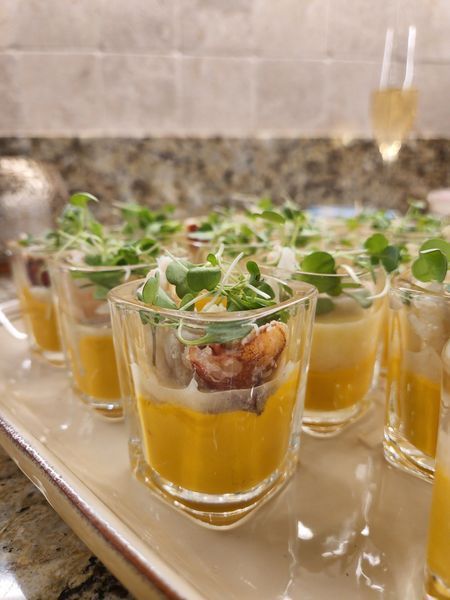 A tray of shot glasses filled with yellow liquid and vegetables