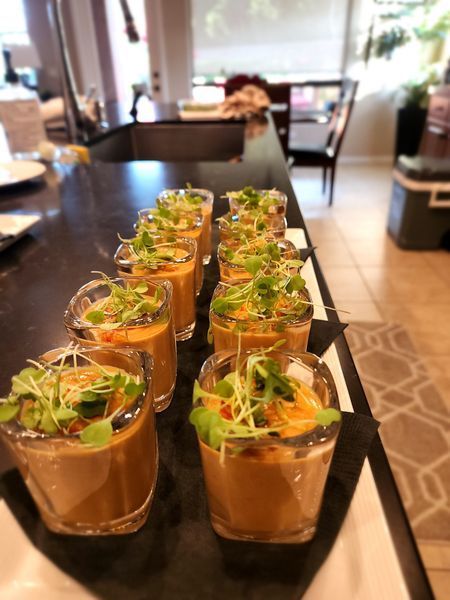 A row of shot glasses filled with soup on a table.