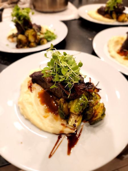 A white plate topped with meat and mashed potatoes