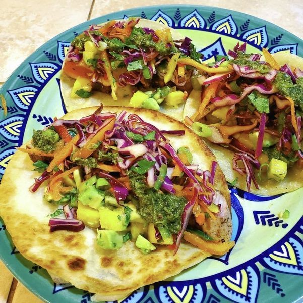 Three tacos with vegetables on a plate with a mandala design