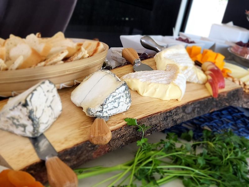 A wooden cutting board with a variety of cheeses on it.