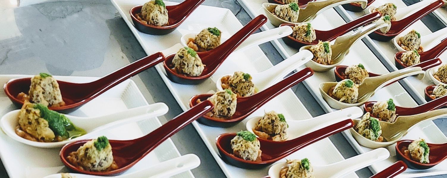A tray of spoons filled with food on a table.