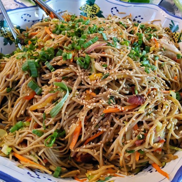 A bowl of noodles with vegetables and sesame seeds