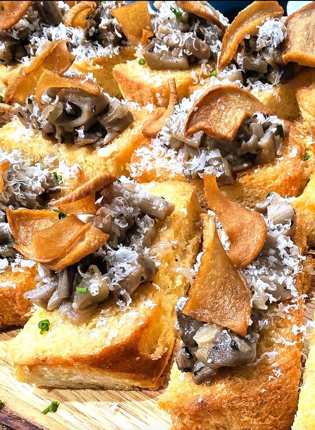 Toasted bread topped with mushrooms and parmesan, garnished with golden crisps.