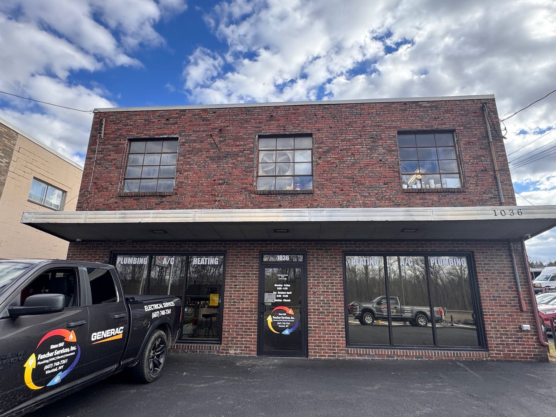 Man in red uniform fixing a white heat pump outside, tools nearby.