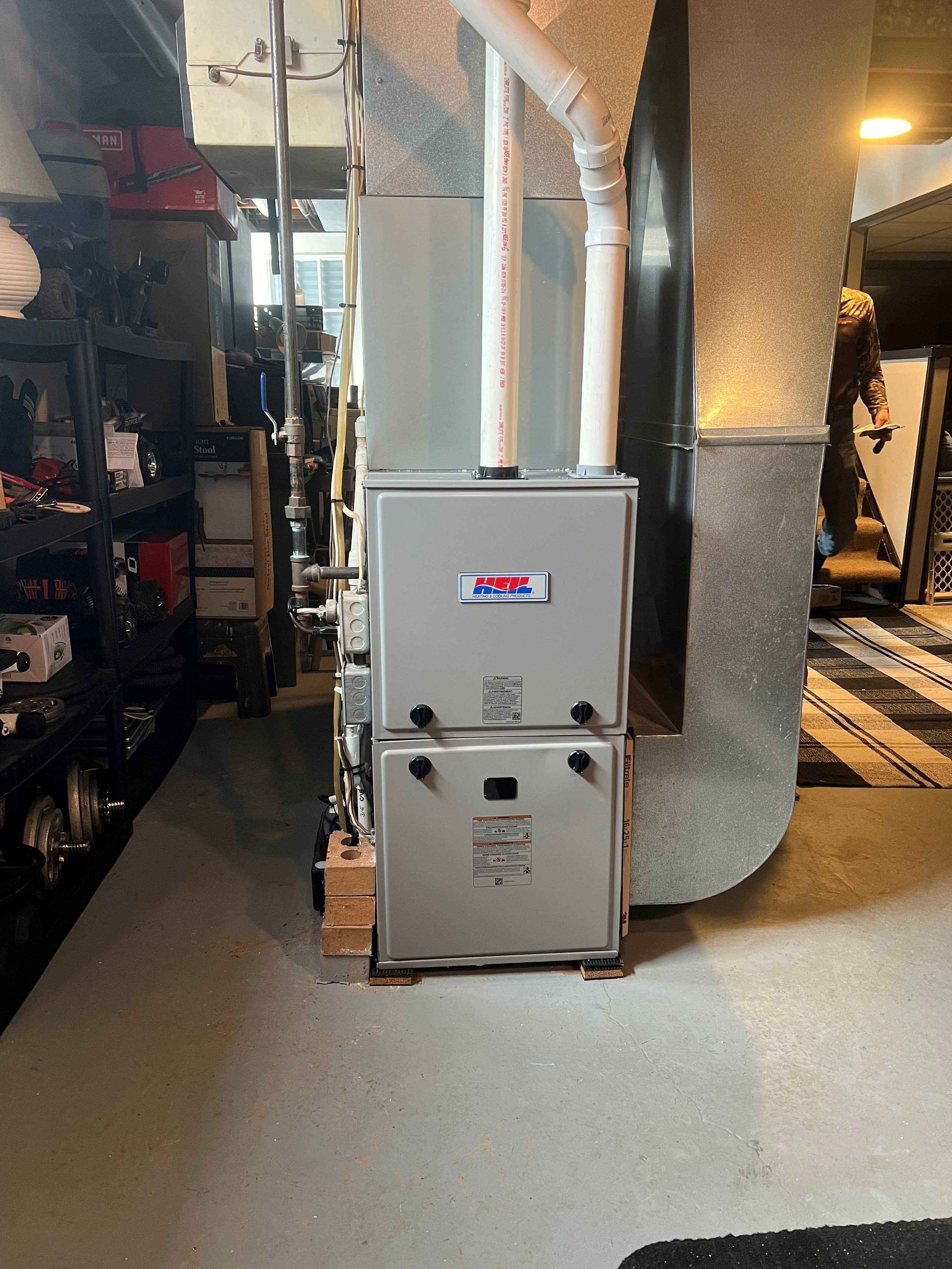 A furnace is sitting in a basement next to a wall.