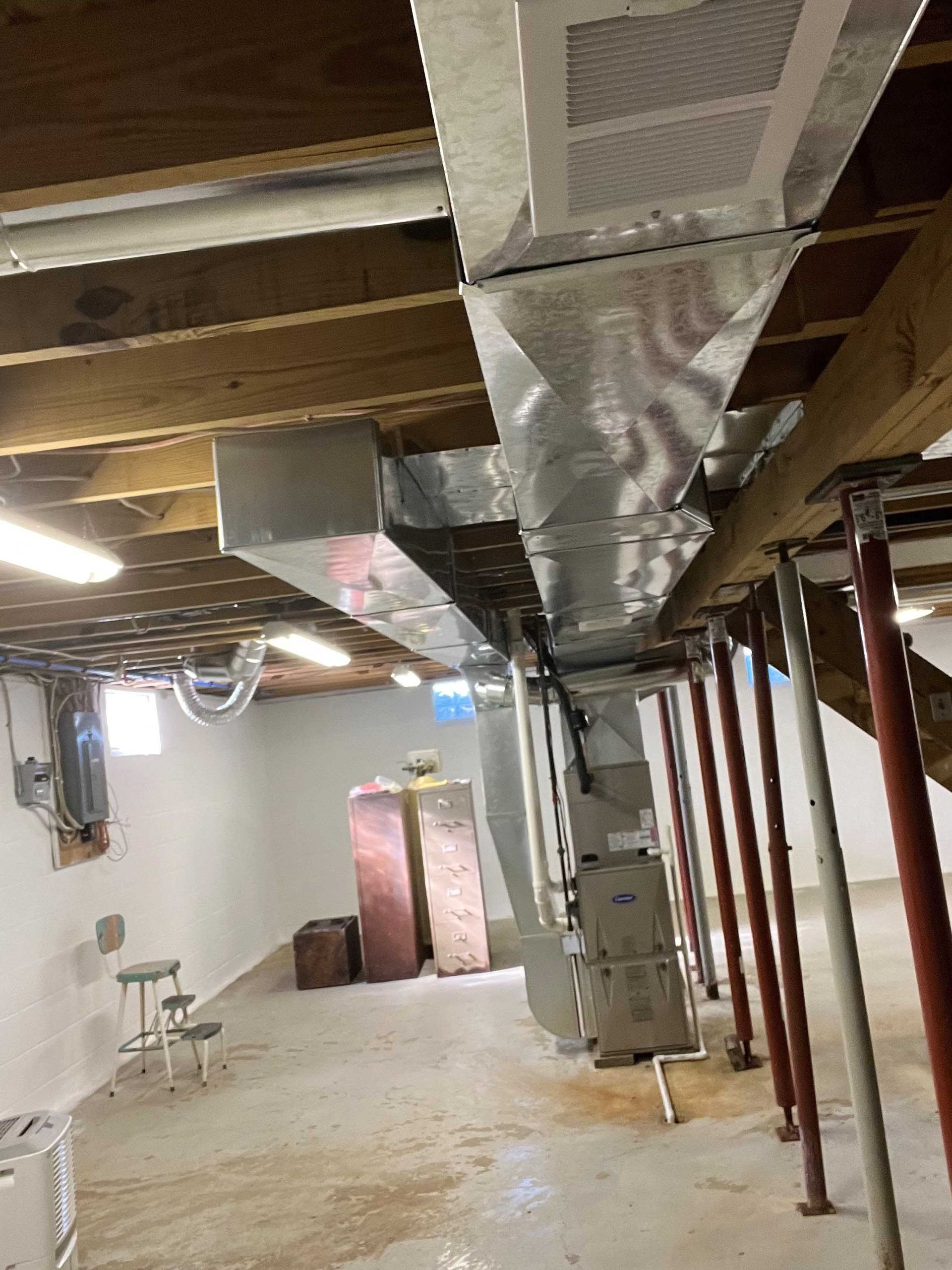 A basement with a lot of pipes coming out of the ceiling.