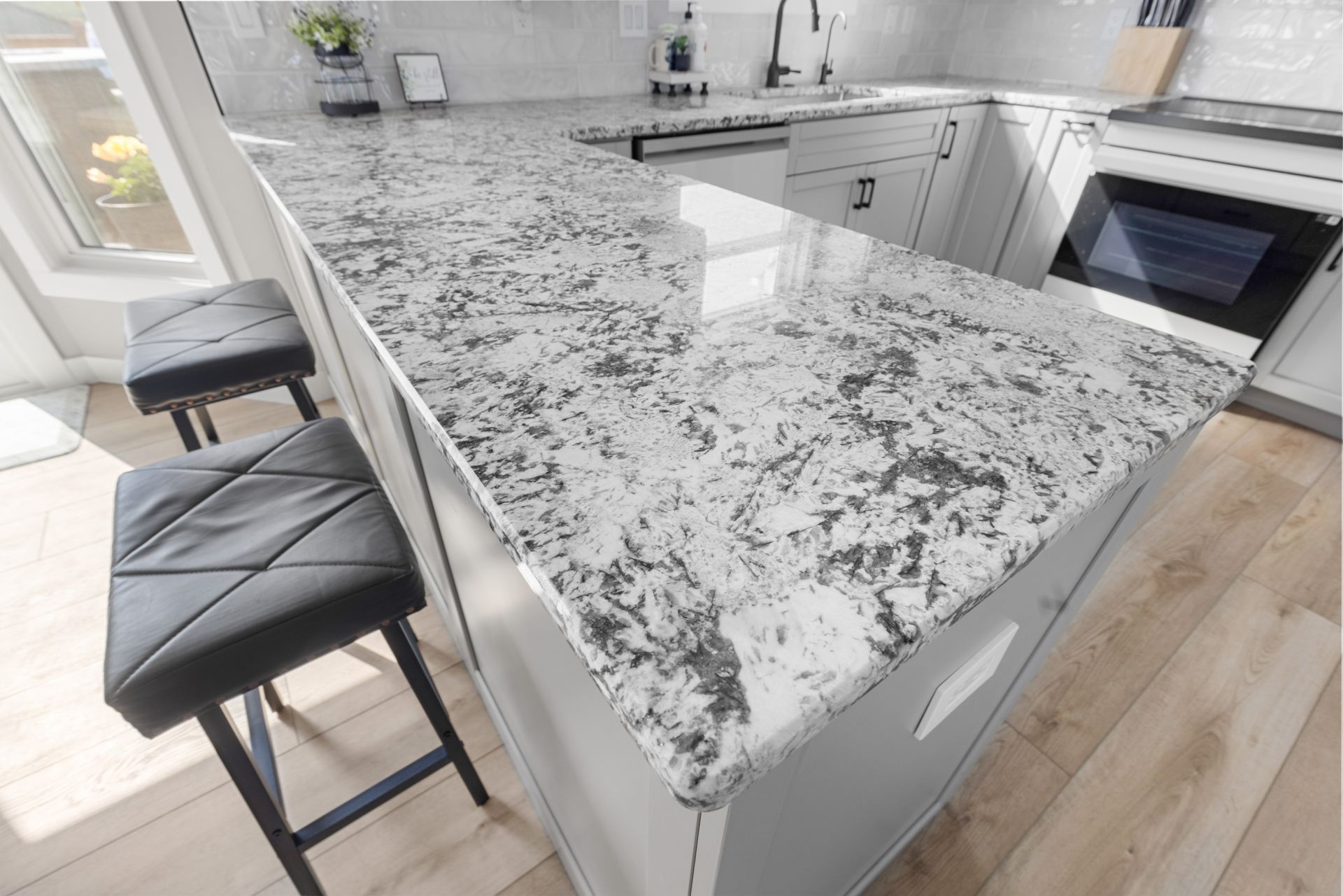 Kitchen island with granite countertop and black stools.