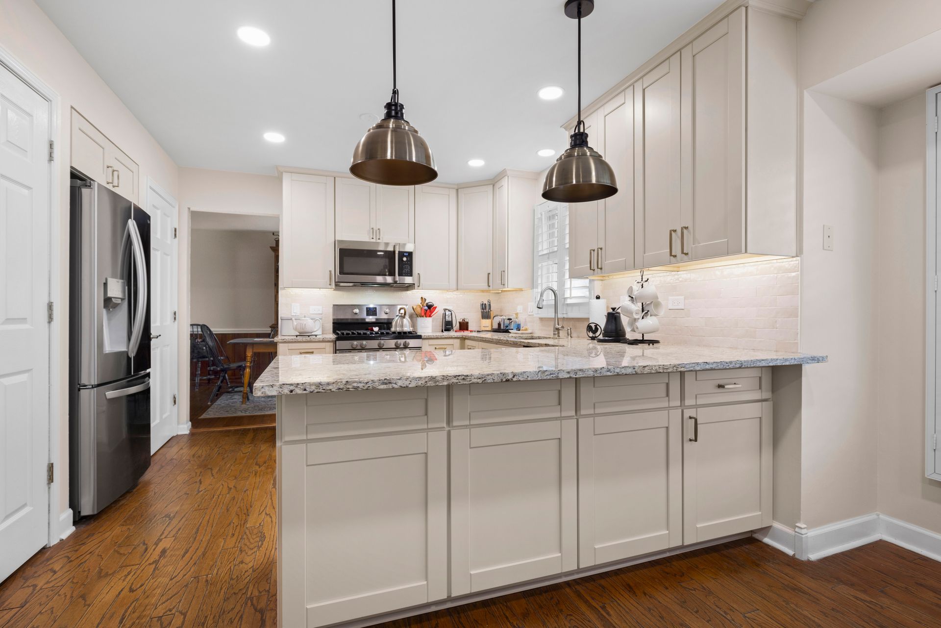 Modern kitchen with beige cabinets, granite countertops, and pendant lights.