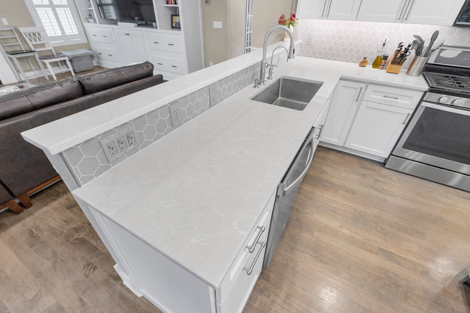 Modern kitchen with light countertops and white cabinets; island with sink.